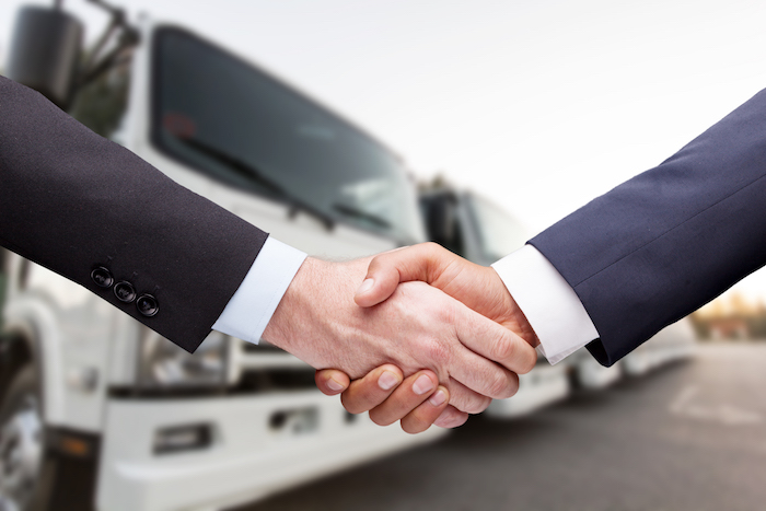 Two businessman handshaking front of the trucks,